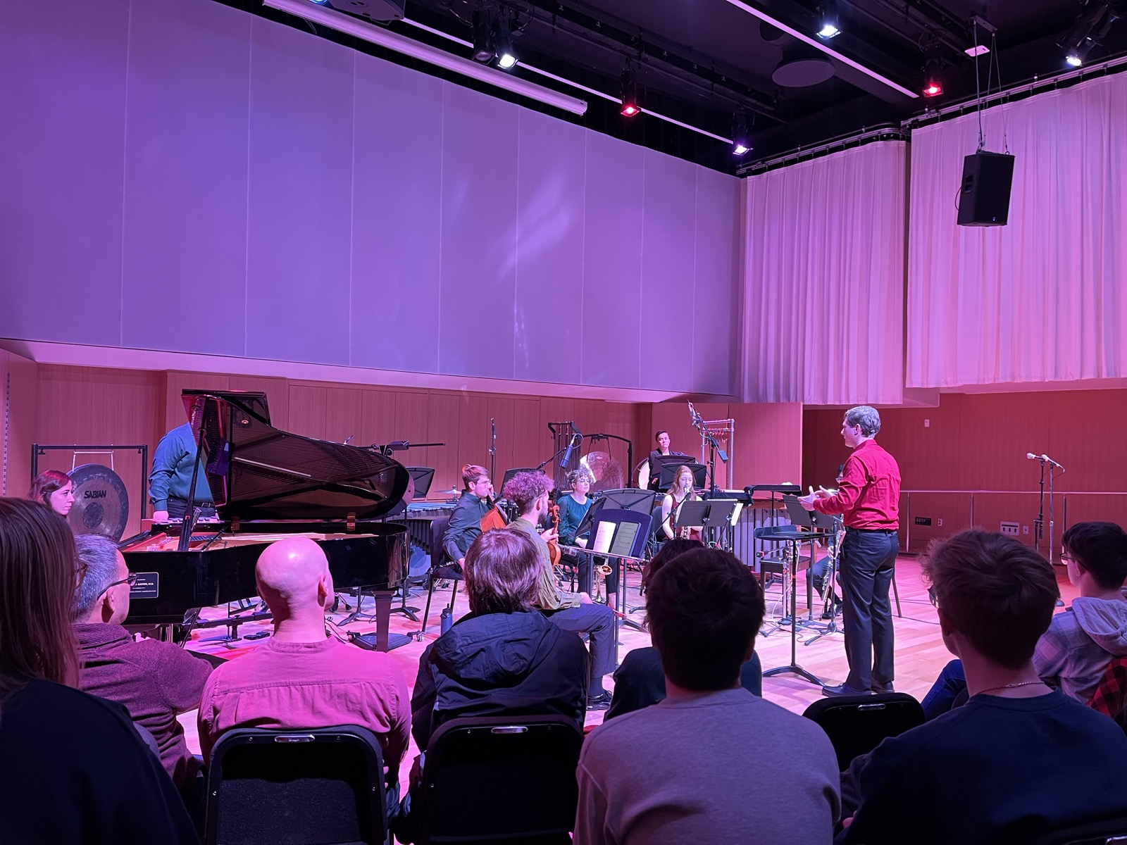 The ensemble performing under magenta stage light