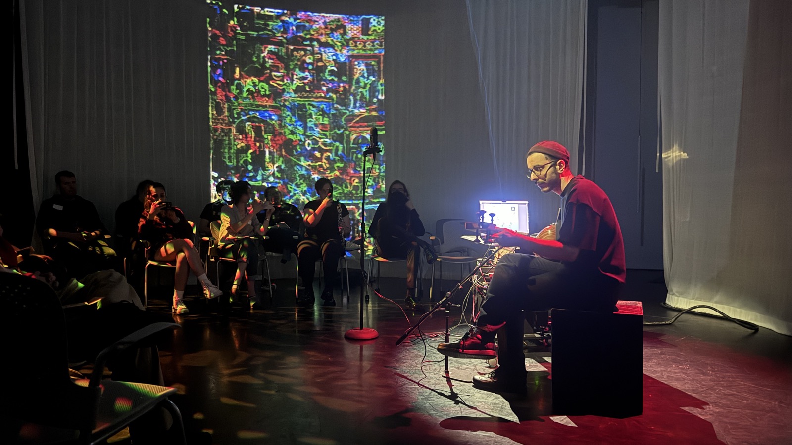 Performing with tar and laptop in front of projected visuals