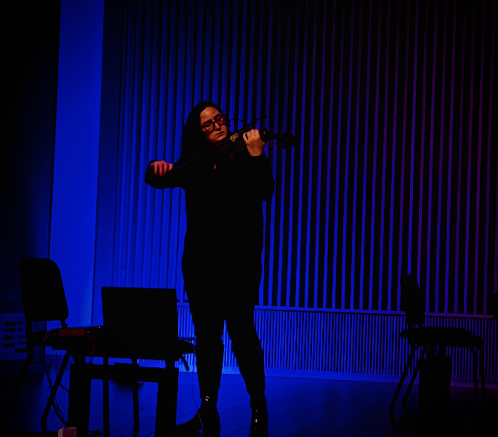 The violinist performing under blue stage light